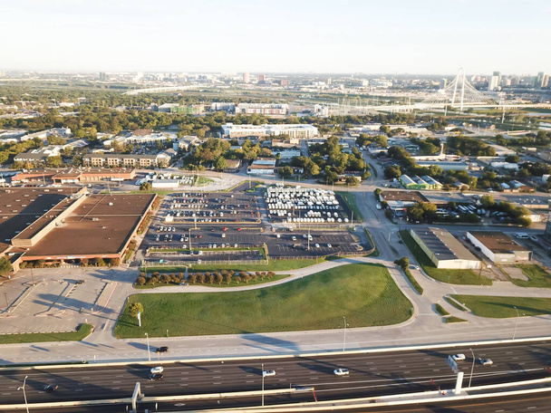 Parque de negocios y zona industrial a lo largo de la I-30 Tom Landry Freeway al oeste del centro de Dallas con Margaret Hunt Hill Bridge en segundo plano. Shell edificio industrial grandes estacionamientos al aire libre - Foto, Imagen