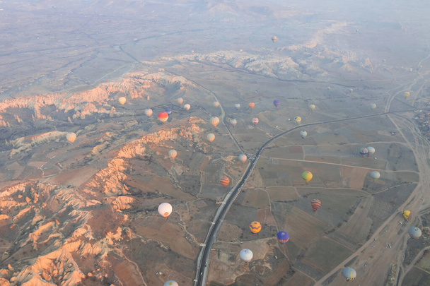 Hodně horkovzdušných balónů letí nad údolím se silnicí v Cappadocii. Letecká fotografie - Fotografie, Obrázek