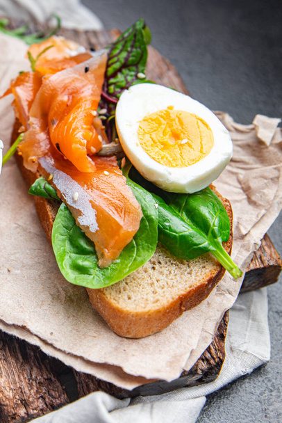 サンドイッチ卵サーモンスモアブロードグリーンサラダミックス魚介類オープン新鮮な部分食事テーブルの上のスナックコピースペースフードの背景  - 写真・画像