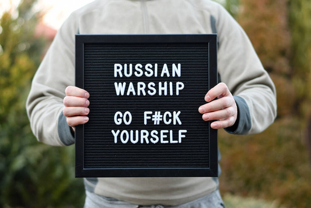 Man holding a letterbox with citation "Russian warship go f#ck yourself". War in Ukraine - Foto, imagen