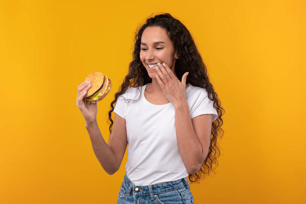 Happy Latin Lady gospodarstwa hamburgery lizanie palec w studio - Zdjęcie, obraz