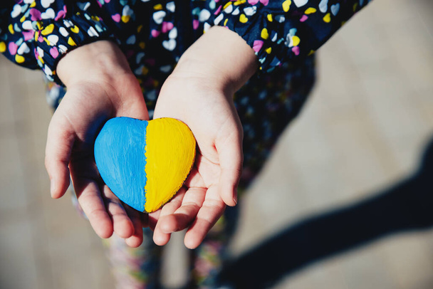 Pieni pieni lapsi pitää sydämen muotoinen kivi Ukrainan lippu tai hymni - Valokuva, kuva
