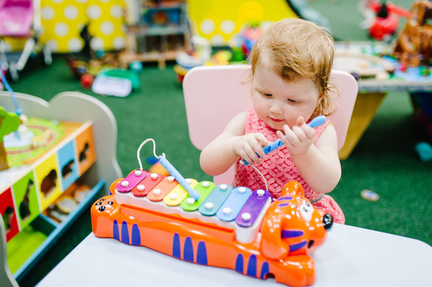 Happy little kid, child, baby girl one year, plays a musical instrument xylophone in children's room for birthday or home. Game center. - Zdjęcie, obraz