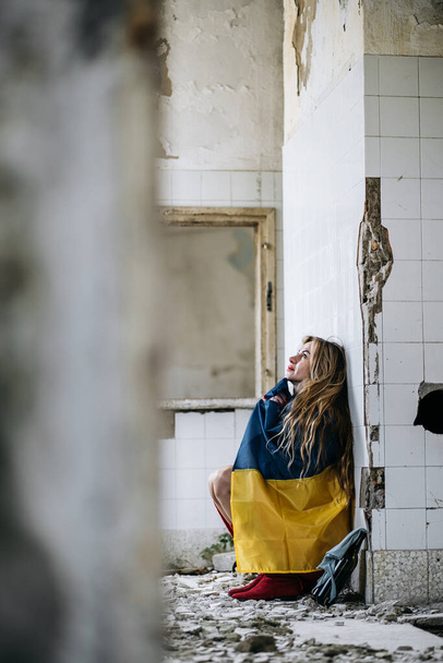 A Ukrainian woman in a ruined house. Flag of Ukraine. Stop War - Zdjęcie, obraz