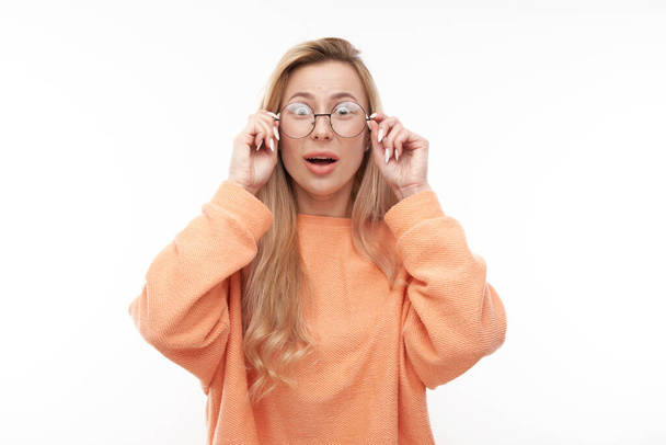 Shocked blond girl face with glasses looks surprised close-up on white studio background with copy space - Photo, Image