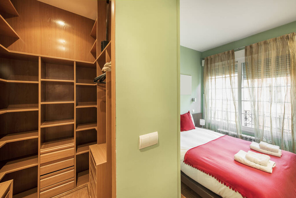 Bedroom with walk-in closet with wooden shelves and chest of drawers in a vacation rental apartment - Valokuva, kuva