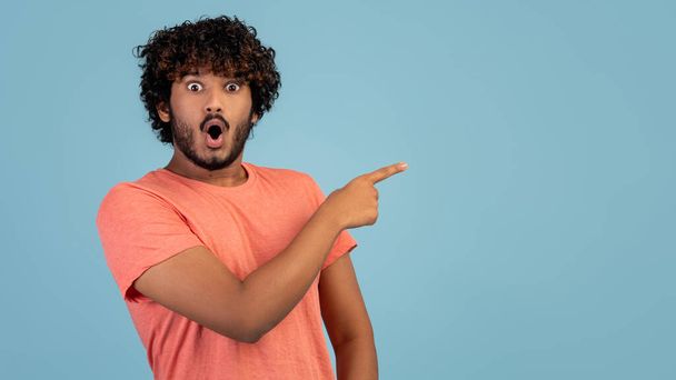 Emotional indian guy pointing at copy space - Фото, изображение