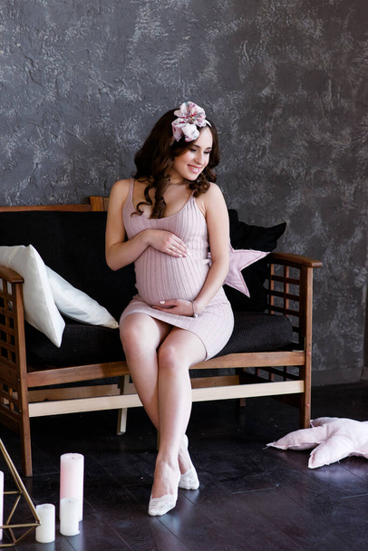 Peaceful happy expecting mom wearing stylish linen dress, touching big belly, smiling with closed eyes, hugging caressing tummy, feeling kicks. Expectation, pregnancy, clothes for expecting concept - Fotó, kép