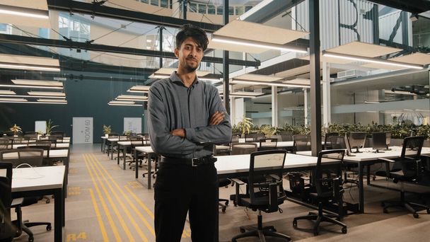 Ινδός αρχηγός του γενικού γραφείου επαγγελματίας εργάτης Άραβας επιχειρηματίας στέκεται στο γραφείο με τα χέρια σταυρωμένα αυτοπεποίθηση ισχυρή θέση διευθυντής του έργου θέτουν ποζάρουν στο χώρο εργασίας με σταυρωμένα χέρια - Φωτογραφία, εικόνα