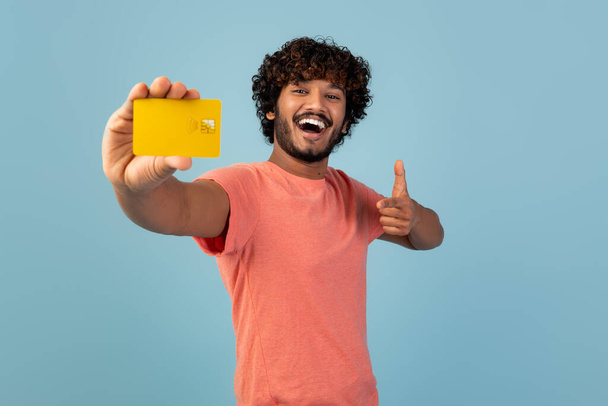 Happy hindu guy pointing at credit card in his hand - Фото, изображение
