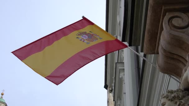 İspanya bayrağı eski bir binanın duvarında asılı ve mavi gökyüzüne karşı rüzgarda dalgalanıyor. - Video, Çekim