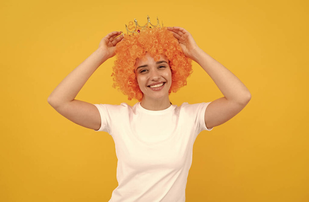 Смотри, что у меня есть. Посетитель дня рождения. счастливая смешная женщина в кудрявом парике и короне. - Фото, изображение