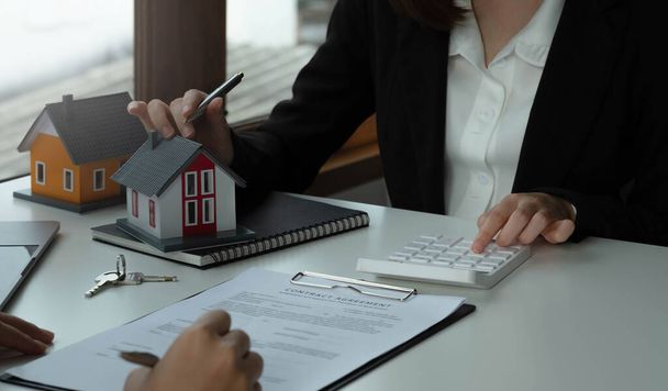 Real Estate concept, Agent houdt calculator voor de huidige prijs voor lening investering grafiek documenten en het berekenen van tabel betaling aan custome - Foto, afbeelding