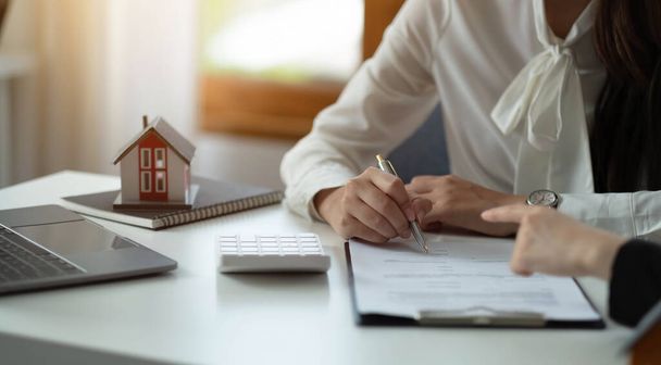 Модель дома с агентом и клиентом обсуждается для контракта на покупку, получить страхование или кредит недвижимости или собственности - Фото, изображение