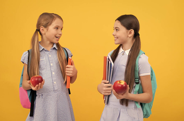 Onnelliset lapset ystävät takaisin kouluun pitämällä kirjoja ja omenoita terveelliseen ruokavalioon, ruokavalioon - Valokuva, kuva
