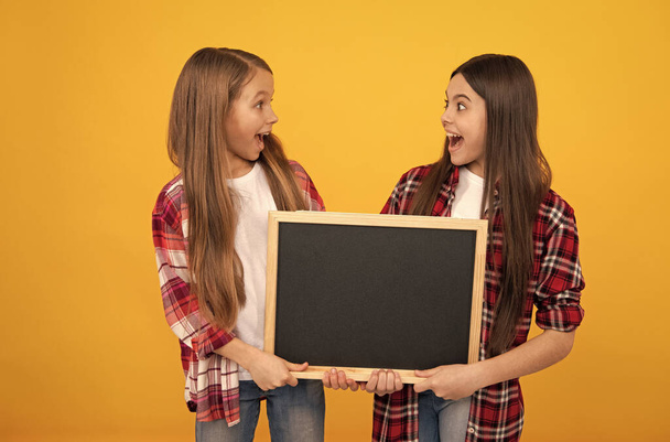 geschockte Kinder in lässig karierten halten Schultafel für Kopierraum, Promotion - Foto, Bild