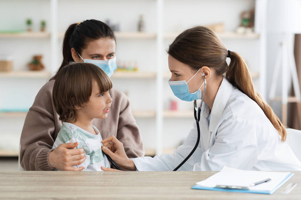 Professional woman pediatrician listening little boy heart beating with stethoscope, checking up health condition - Photo, Image