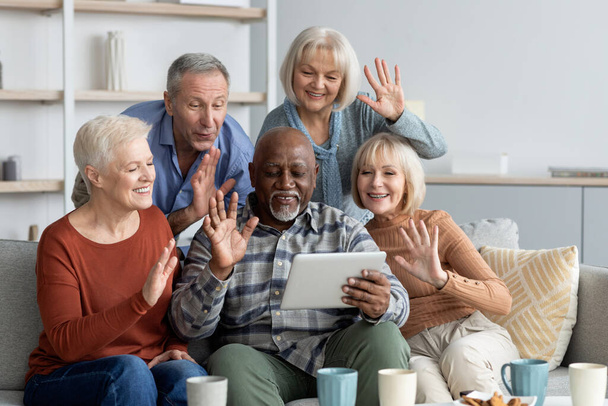 Позитивные многорасовые старшие друзья проводят видеоконференцию, используя площадку - Фото, изображение