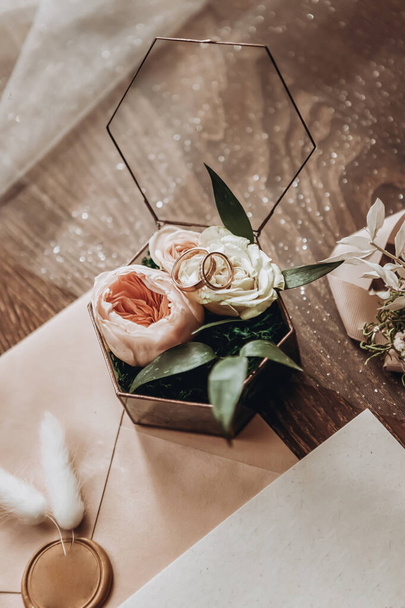 Alyanslar, düğün aksesuarı olarak çiçeklerle dolu güzel bir kutunun üzerinde duruyor. - Fotoğraf, Görsel
