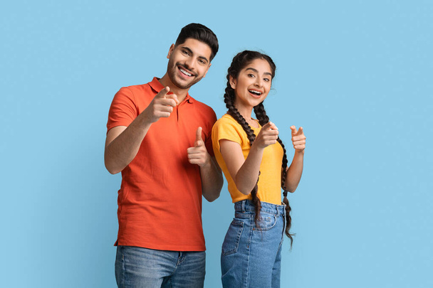 Positive middle eastern man and woman pointing at camera with fingers - Photo, Image