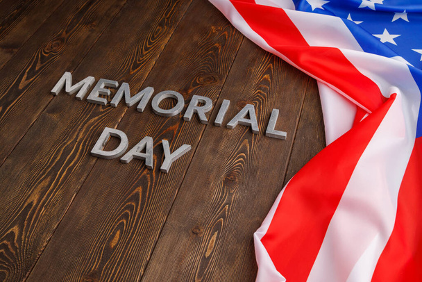 the words memorial day laid with silver metal letters on wooden board surface with crumpled usa flag - Zdjęcie, obraz