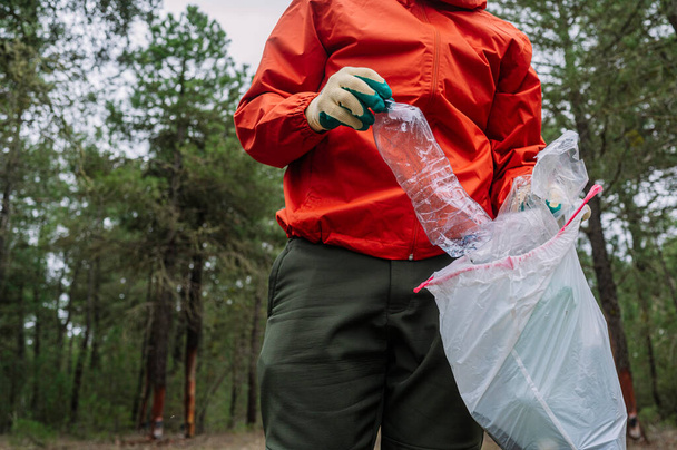 Hombre que recoge basura y plásticos en el bosque. - Foto, imagen