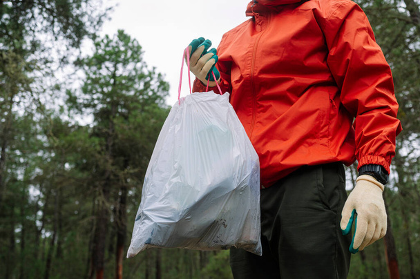 Ο άνθρωπος που συλλέγει σκουπίδια και πλαστικά στο δάσος. - Φωτογραφία, εικόνα
