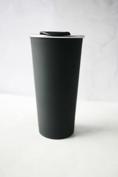 czarny kolor wielokrotnego użytku eko filiżanka kawy na stole z miejsca do kopiowania. - Zdjęcie, obraz