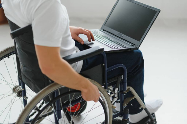 Man in wheelchair working on laptop in living room. - Foto, Imagem