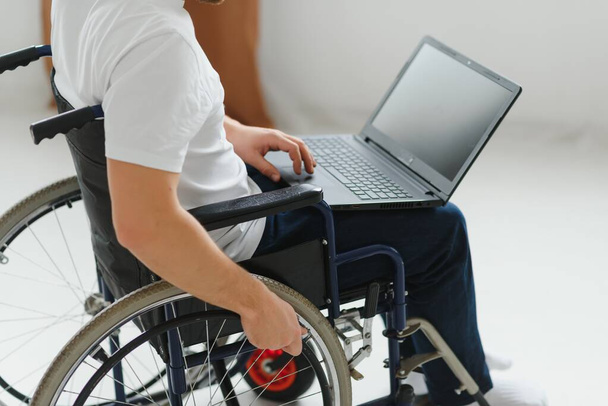 Portrait of smiling Person with a disability sitting in wheelchair and working on laptop from home. Freelancer concept. - Foto, immagini