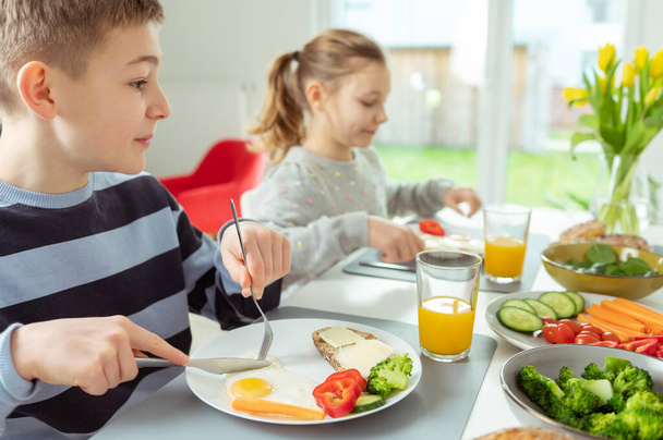 Teen brother and sister eating healthy breakfast at home before school - Photo, image