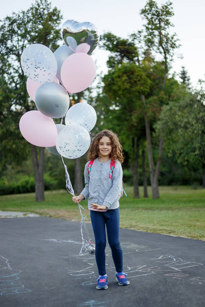 Pełna długość obrazu uroczej uczennicy cute w parku gry i trzymając balony w parku. - Zdjęcie, obraz