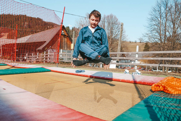Ένα αγόρι πηδάει σε ένα τραμπολίνο σε μια παιδική χαρά στην Αυστρία. - Φωτογραφία, εικόνα