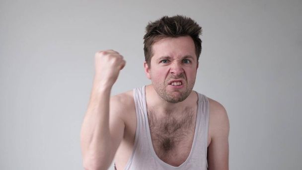 Alcoholic man showing his fist and shouting with angry expression, over gray background. Home family tyrant. Come on, attack, I will beat you. - Photo, Image