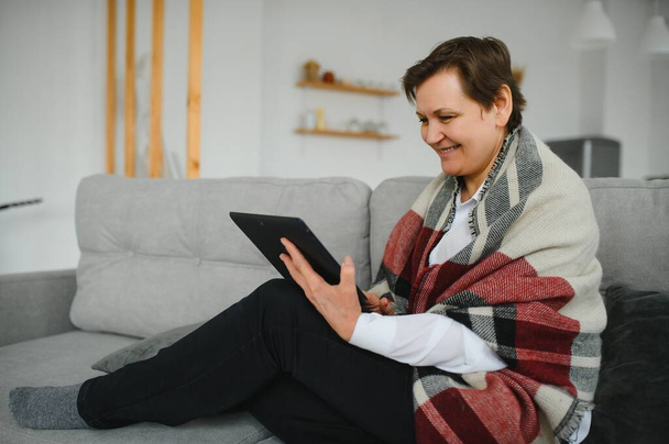pretty senior woman using tablet computer at home - 写真・画像