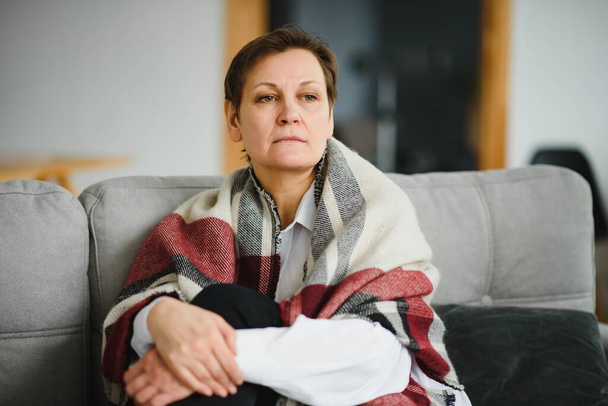 portrait of senior woman at home on sofa with plaid - Fotografie, Obrázek