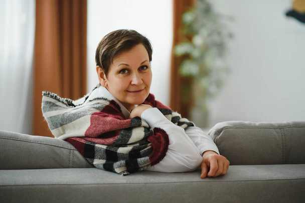 Mature Woman. Beautiful Healthy Middle Age Female Sitting On Sofa At Home. Beauty And Comfort Concept. - Fotó, kép
