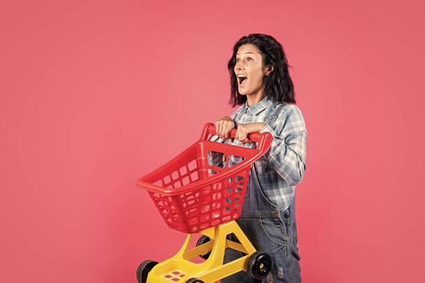 Pleasant shopping. happy girl hold shopping cart. Buyer in supermarket. customer with empty cart. female shopper with trolley in supermarket. woman shopping in supermarket pushing trolley - Foto, Imagem