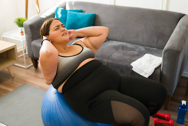 Kimerült kövér nő, aki pilates edzést tart otthon. Fáradt stressz nagy nő gyakorlása, hogy lefogy - Fotó, kép