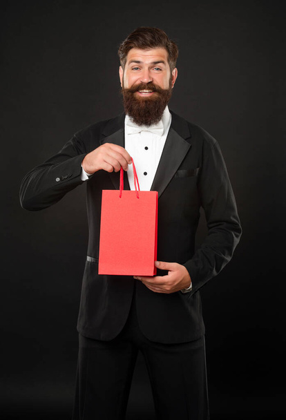 laughing man in tuxedo bow tie on black background with shopping bag for mens day. copy space. - Фото, зображення