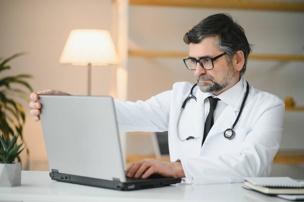 Retrato del médico senior en bata blanca en el lugar de trabajo - Foto, Imagen