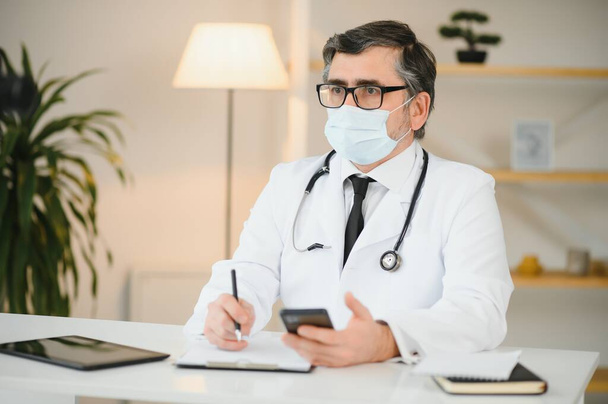 male doctor with medical face mask and a stethoscope at clinic. - Foto, Bild