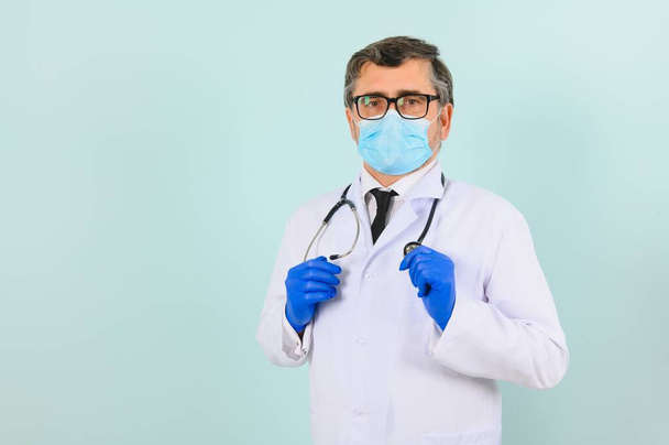 Portrait of a male doctor in a mask and gloves on a blue background. Healthcare concept. - Photo, image