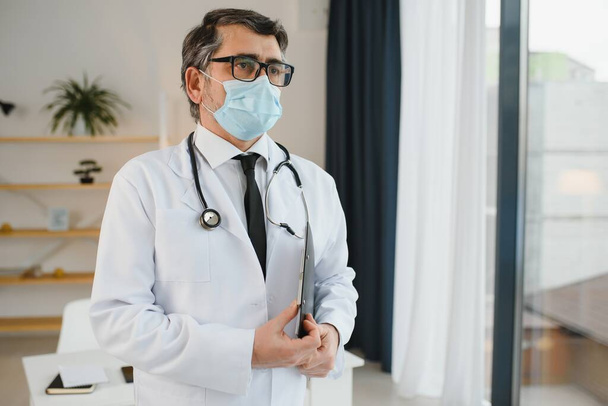 male doctor with medical face mask and a stethoscope at clinic. - Valokuva, kuva