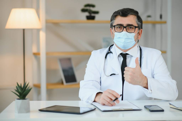 male doctor with medical face mask and a stethoscope at clinic. - Foto, immagini