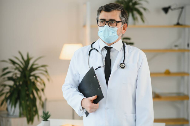 male doctor with medical face mask and a stethoscope at clinic. - Fotoğraf, Görsel