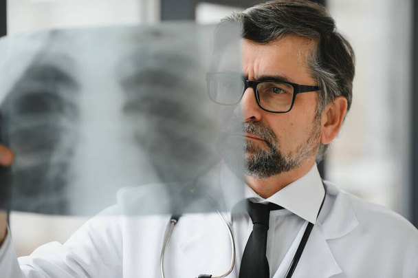 A senior doctor looking at the X-ray in his office - Φωτογραφία, εικόνα
