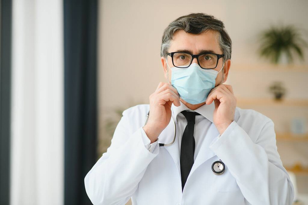medico maschio con maschera medica e stetoscopio in clinica. - Foto, immagini