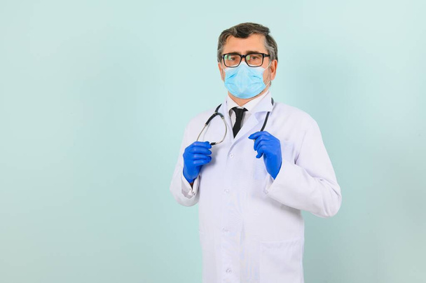 Man in medical gloves putting on protective face mask against blue background - Foto, imagen