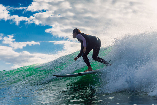 15 février 2022. Brésil, Florianopolis. Femme en combinaison pendant le surf avec la lumière du matin. Surfeuse professionnelle sur planche de surf. - Photo, image